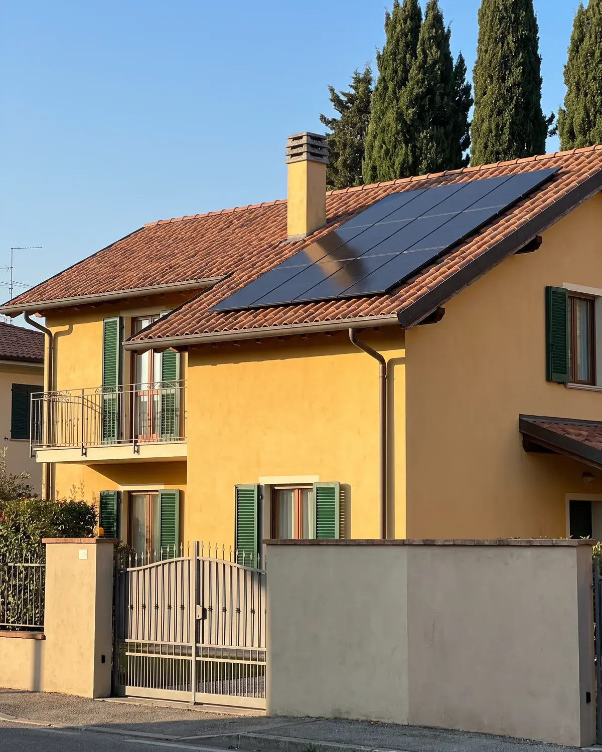 Villetta in intonaco giallo con tetto in coppi e moduli fotovoltaici LONGi full black